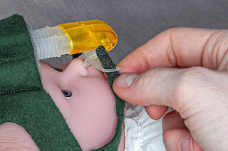 Layer A - 5. Seitliches Anziehen der Maske (Prong) über der Nase des Kindes